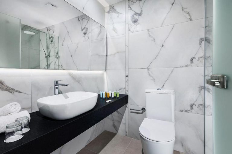 Baño de lujo con paredes de mármol blanco, lavabo sobre encimera y amenities en Mayfair Hotel