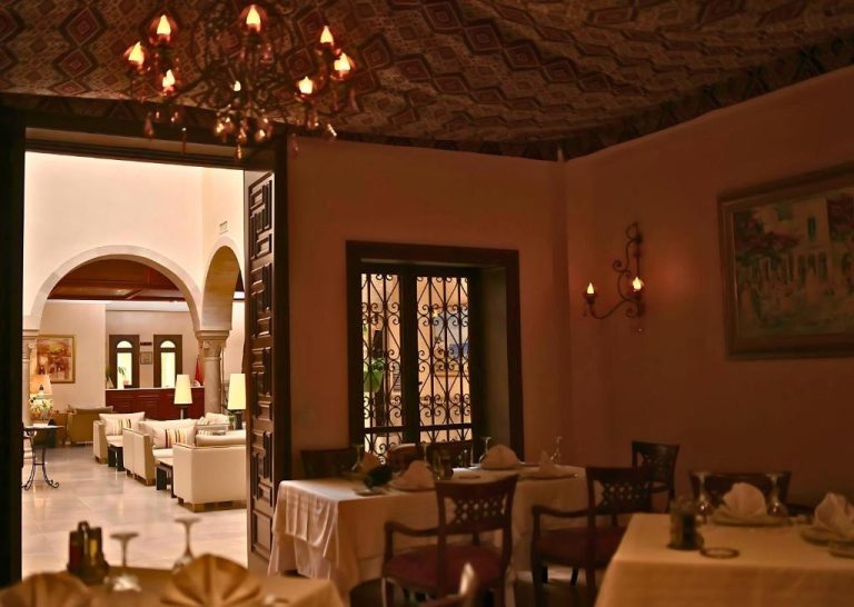 Elegante restaurante interior del Hotel Borj Dhiafa con mesas preparadas, araña de luces y techo decorado