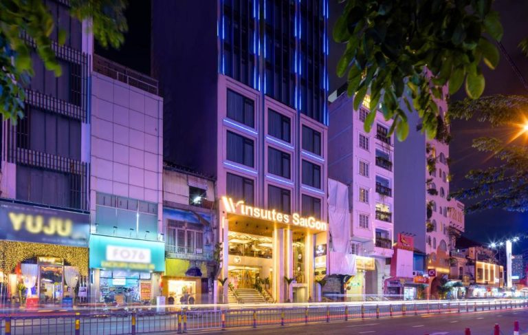 Fachada nocturna iluminada del Winsuites Saigon Hotel en Ho Chi Minh City con luces azules