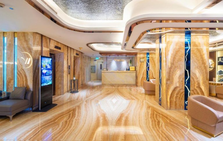 Lujoso lobby con suelos y paredes de mármol dorado en el Winsuites Saigon Hotel de Vietnam