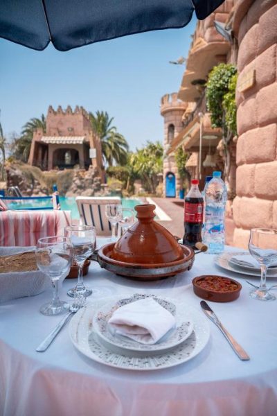 Mesa con tajín marroquí en la terraza restaurante con vistas a la piscina del Lakala Complexe Touristique