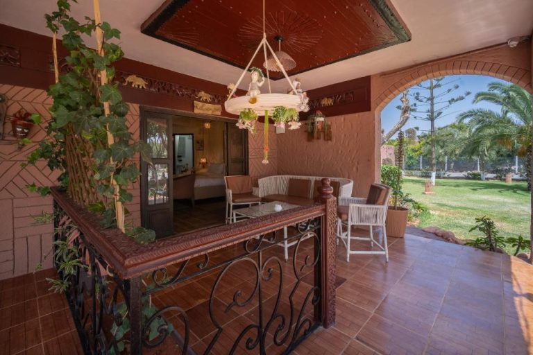 Terraza cubierta con mobiliario de ratán y vistas al jardín tropical en Lakala Complexe Touristique