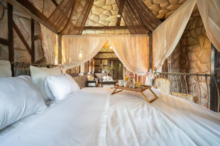 Habitación de lujo con cama de dosel y paredes de piedra en Lakala Complexe Touristique