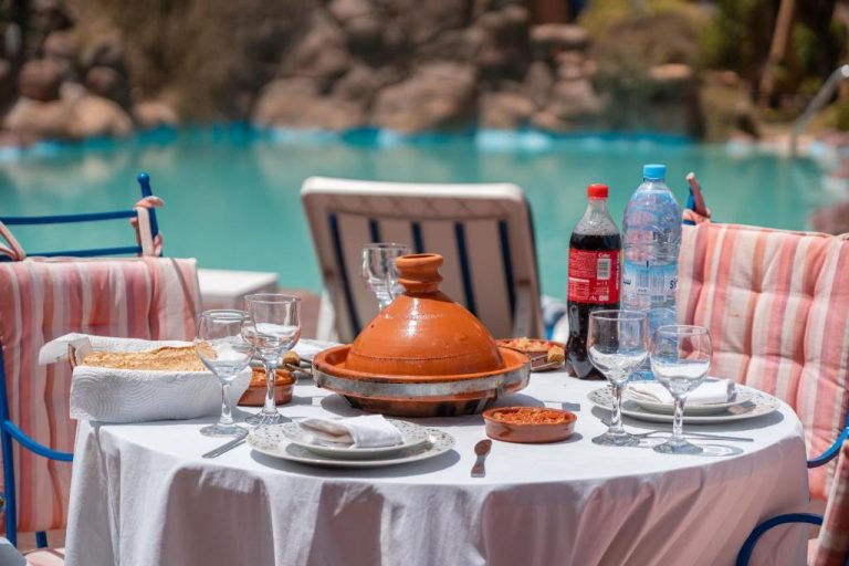 Mesa con tajín marroquí junto a la piscina del Lakala Complexe Touristique en Marruecos