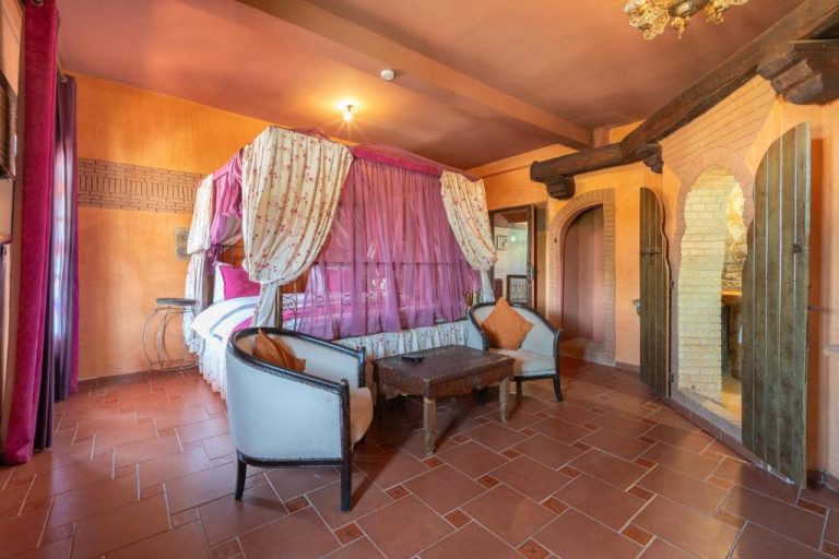 Habitación de lujo con cama de dosel rosa y zona de estar en Lakala Complexe Touristique