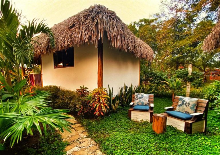 Cabaña con techo de palapa y jardín tropical en Hotel Cabañas Puesta del Sol