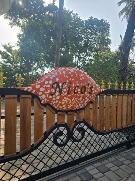 Cartel de bienvenida con forma de pez del Hotel Nico's en la entrada principal con verja decorativa