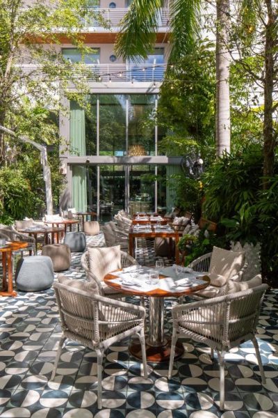 Terraza exterior del restaurante Mr C Miami Coconut Grove con mesas elegantes y jardín tropical