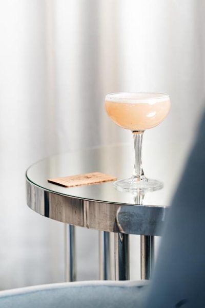 Elegante cóctel rosado en copa coupe sobre mesa cromada del Mr C Miami Coconut Grove