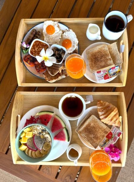 Desayuno completo servido en bandeja con huevos, frutas, tostadas y zumo en Erawan Villa Hotel