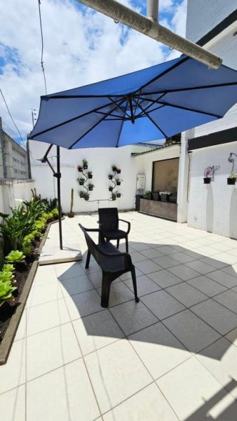 Terraza exterior con sombrilla azul y sillas en Altamira Apart Suites, zona de descanso al aire libre