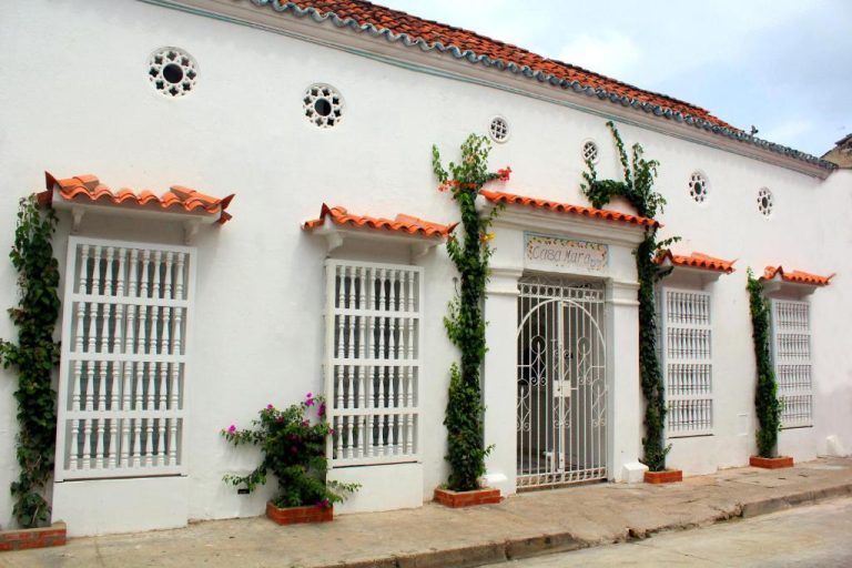 Fachada colonial blanca con vegetación y puerta de hierro del Hotel Casa Mara by Akel Hotels