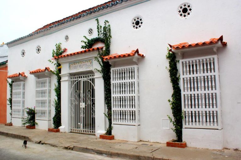 Fachada colonial blanca con ventanas de madera y jardín trepador del Hotel Casa Mara By Akel Hotels