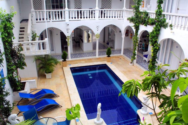 Piscina interior en el patio colonial del Hotel Casa Mara by Akel Hotels con arcos blancos y vegetación