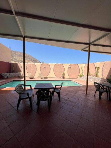 Terraza cubierta con mesas y sillas junto a la piscina exterior del BananaHouse con vistas a la montaña