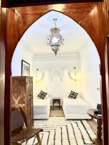Salón con arco árabe tallado y decoración marroquí tradicional en Riad Serendip Marrakech