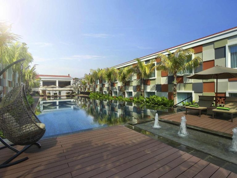 Piscina exterior con fuentes decorativas y tumbonas del Novotel Bali Ngurah Rai Airport