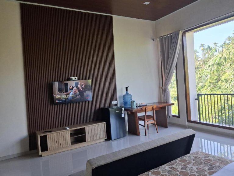 Habitación con TV en pared de madera, escritorio y balcón con vistas a la naturaleza en L'Javas Villas
