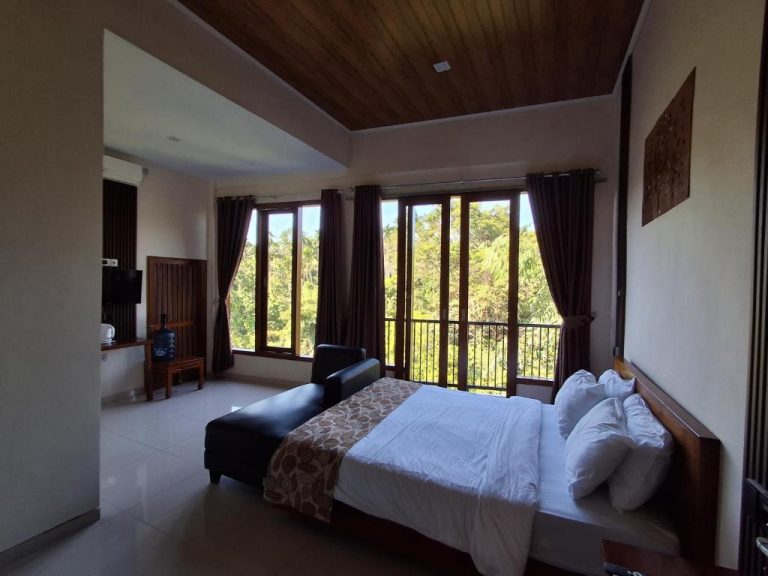 Habitación doble con cama matrimonial, techo de madera y vistas al jardín tropical en L'Javas Villas