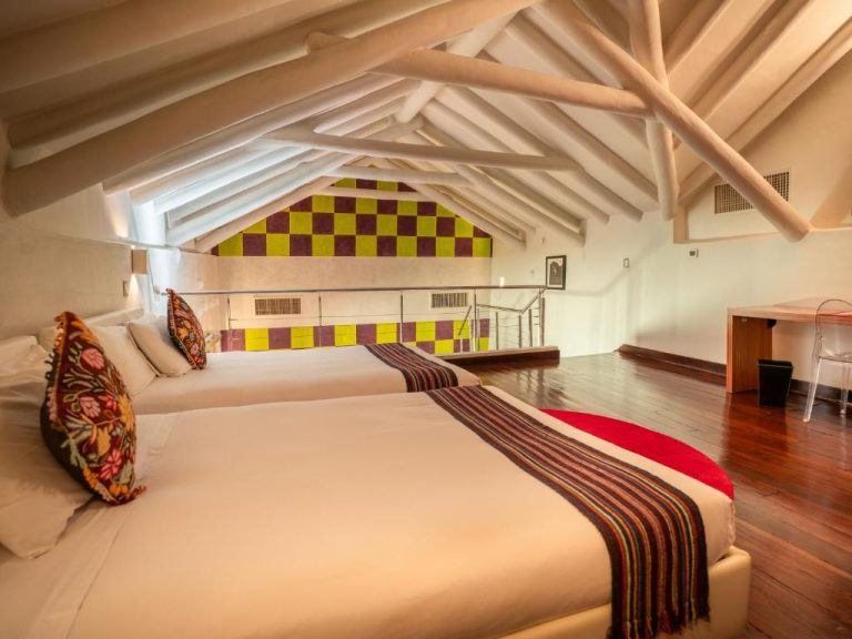 Habitación dúplex con vigas de madera blancas y dos camas en Casa Cartagena Boutique Hotel & Spa