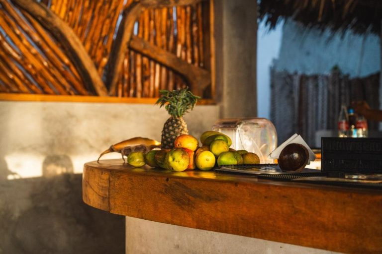 Frutas tropicales frescas como mangos y piña en la recepción de madera del Dhow Beach Boutique Hotel