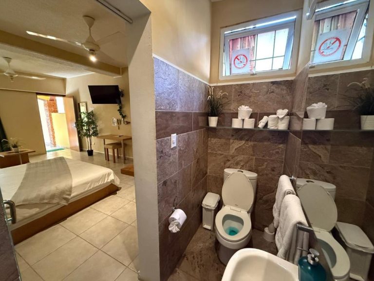 Baño con azulejos de piedra y habitación doble con cama en el Sosua Inn Hotel República Dominicana