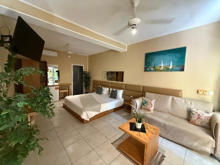 Habitación suite con cama doble, sofá y televisión del Sosua Inn Hotel en República Dominicana