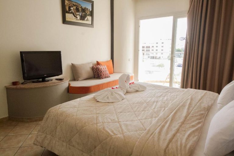 Habitación doble con cama grande, balcón y decoración en tonos naranja del Intouriste Hotel & Suites