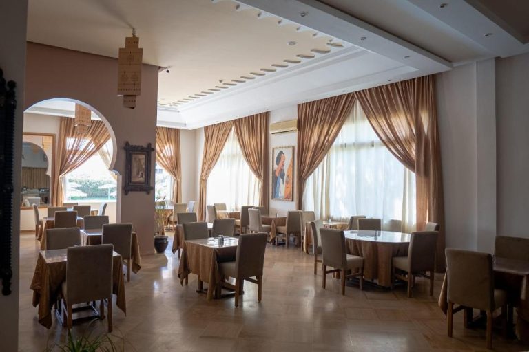 Elegante restaurante del Intouriste Hotel & Suites con mesas dispuestas y cortinas doradas