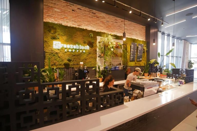Cafetería Breezeblock Coffee con pared de musgo natural y barra de baristas en Downtown Luxe Studio