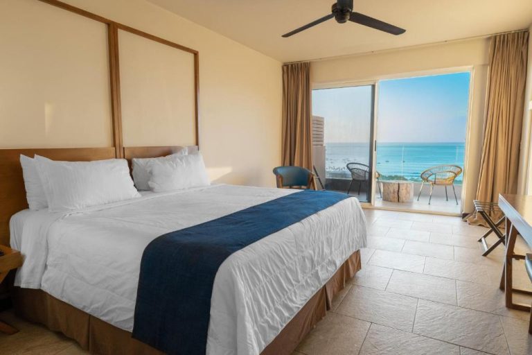 Habitación con cama king y balcón con vista al mar turquesa en el hotel Wyndham Tamarindo