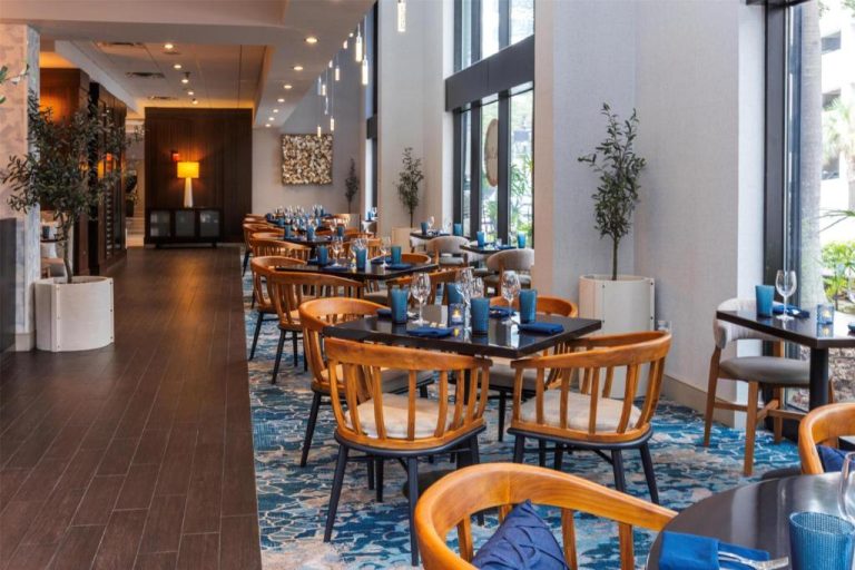 Restaurante interior del Hilton Tampa Downtown con mesas elegantes, sillas de madera y decoración en tonos azules