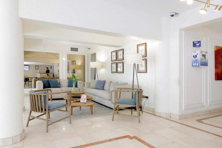 Sala de estar y lobby del MR Express Hotel con sofás blancos, sillones y decoración elegante