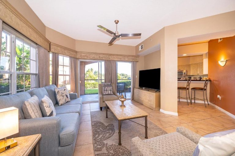 Amplio salón con sofá azul, televisión y cocina americana del apartamento Pura Vida