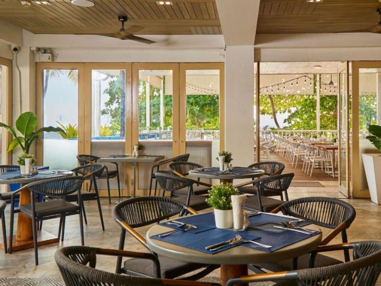 Restaurante interior con terraza exterior del Pullman Pattaya Hotel G con mesas y vistas al jardín