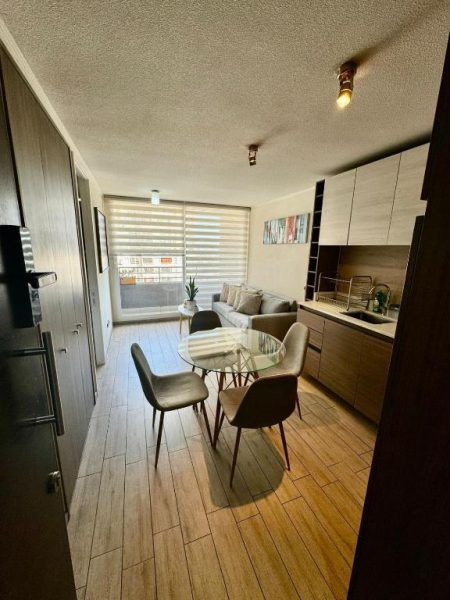 Sala comedor con mesa de vidrio y cocina integrada en apartamento moderno en Santiago Centro
