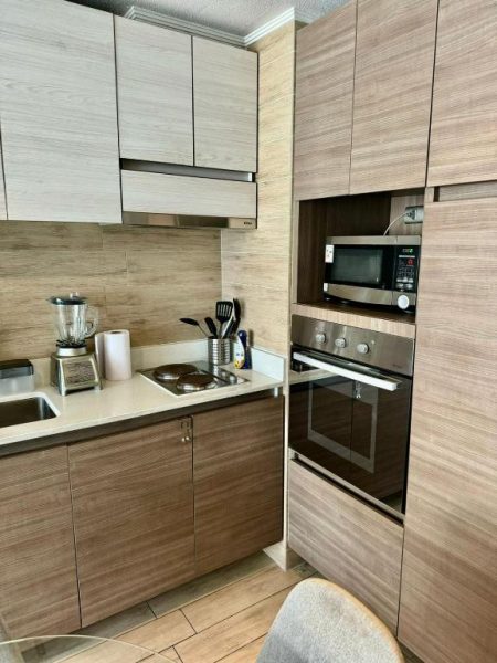 Cocina moderna equipada con horno, microondas y licuadora en apartamento en Santiago centro