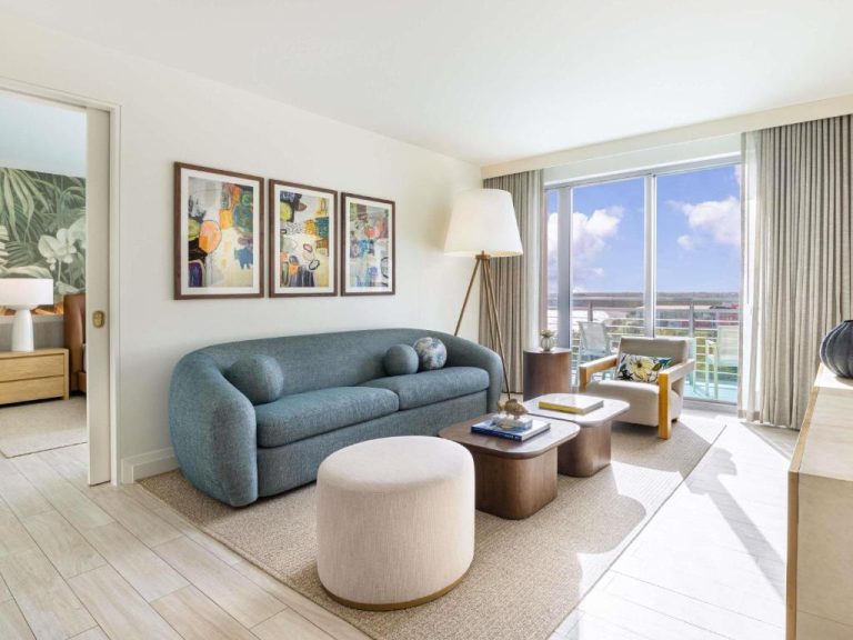 Salón de suite con sofá azul y vistas al mar en el hotel SLS Baha Mar