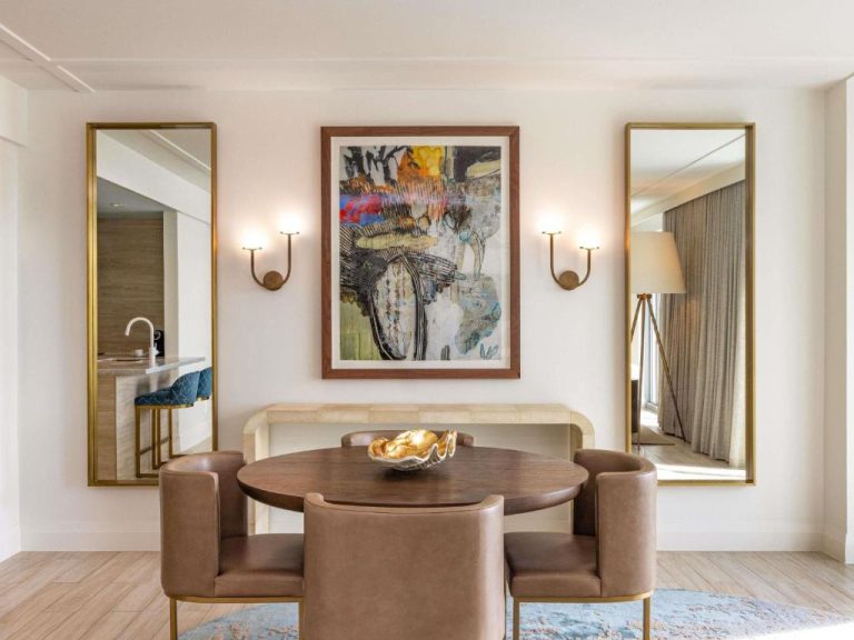 Elegante comedor de suite en SLS Baha Mar con mesa redonda, sillas de cuero y arte contemporáneo