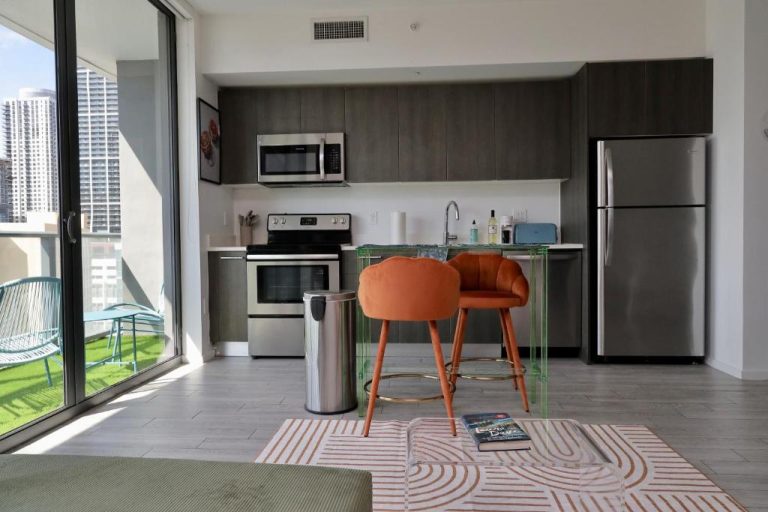 Cocina moderna con electrodomésticos de acero inoxidable y balcón con vistas urbanas en Downtown Luxe Studio