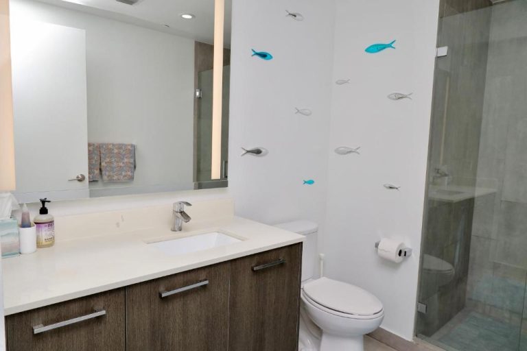 Baño moderno con ducha de cristal y decoración de peces en Downtown Luxe Studio