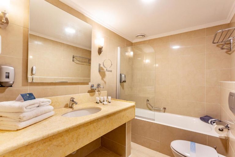 Baño completo con bañera, ducha y encimera de mármol en el Lindos Bay Hotel