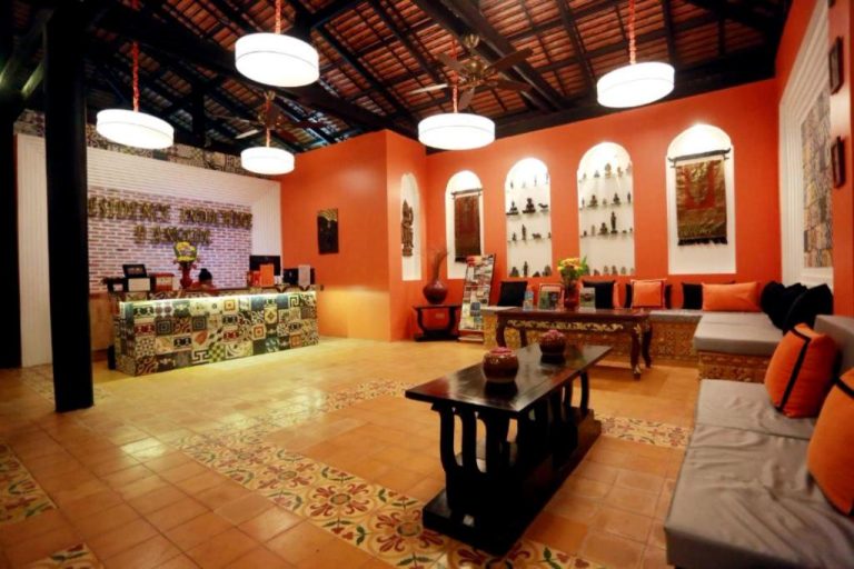 Recepción y lobby de Residence Indochine Suite con decoración colonial, paredes naranjas y estatuas budistas