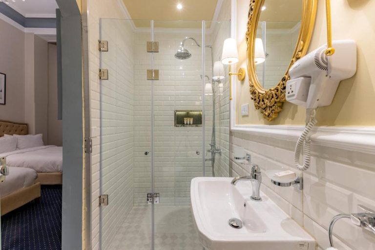 Baño moderno con ducha de cristal y espejo dorado del Cairo Inn The Royal