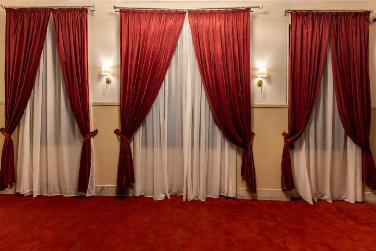 Salón elegante con cortinas rojas y moqueta roja del Cairo Inn The Royal