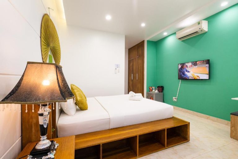 Habitación doble con cama matrimonial, pared verde y TV en Adventure Hotel
