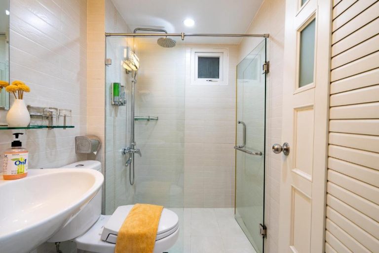 Baño moderno con ducha de cristal, lavabo y aseo del Adventure Hotel