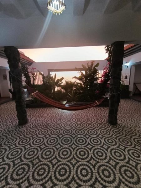 Patio interior con hamaca y plantas tropicales del B&B Casa Boho con suelo de mosaico
