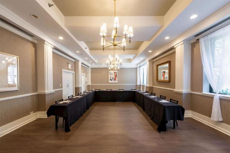 Sala de reuniones en U con mesas negras y araña de luces en Claridge House Chicago Tapestry Hilton