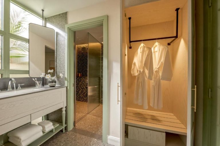 Baño de lujo con vestidor iluminado y albornoces blancos en President Maison Signature by M Village
